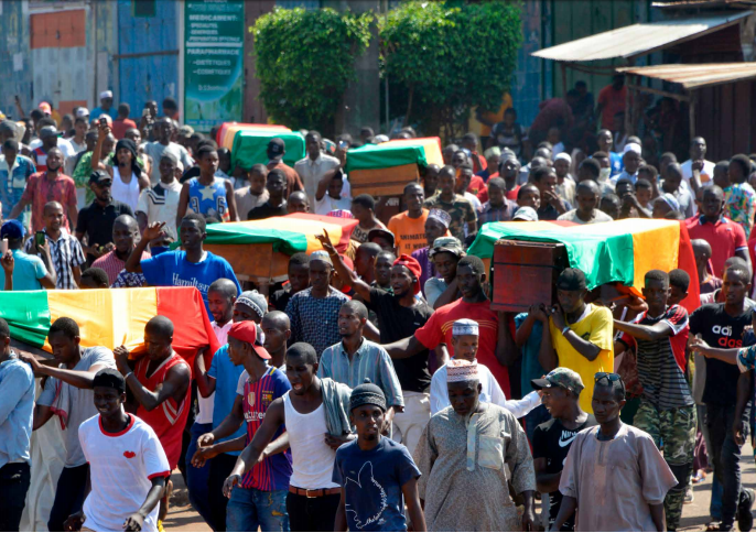 Des personnes portent des cercueils pendant des obsèques après la répression de manifestations de rue, qui a fait au moins 11 morts à Conakry (4 novembre 2019). Le 24 octobre 2019, des foules de manifestant·e·s ont défilé à travers Conakry, la capitale guinéenne, pour protester contre une révision de la Constitution qui devait permettre au président Alpha Condé de briguer un troisième mandat. © CELLOU BINANI/AFP via Getty Images